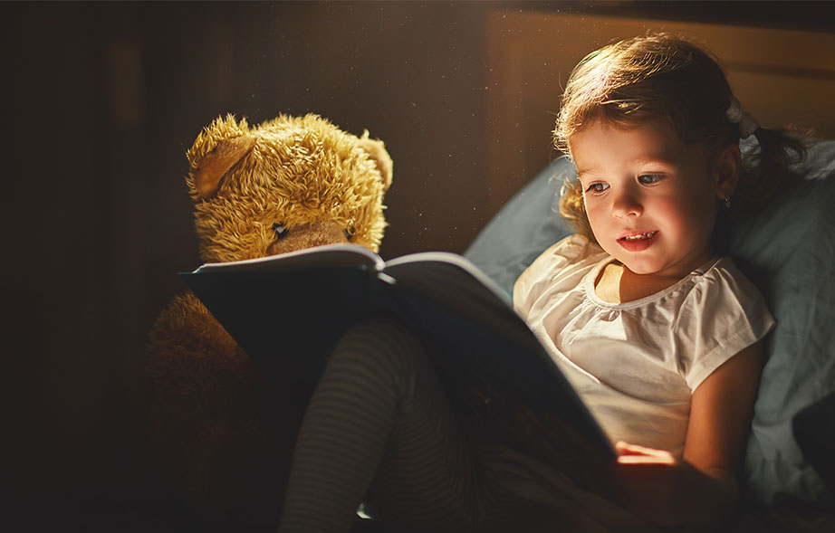 Toddler reading a book in bed